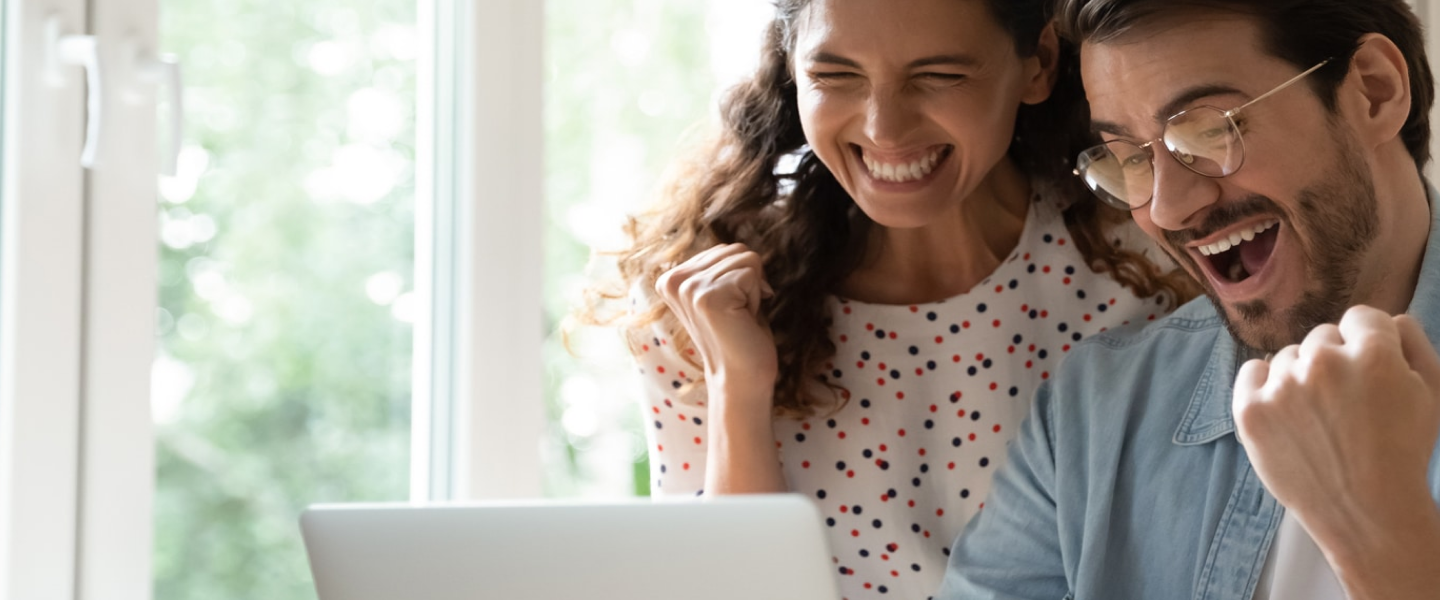 a happy couple ordering on their laptop